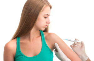 Doctor making insulin or flu vaccination shot by syringe to a young woman