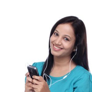 Beautiful young Indian woman listening music with earphones by smart phone